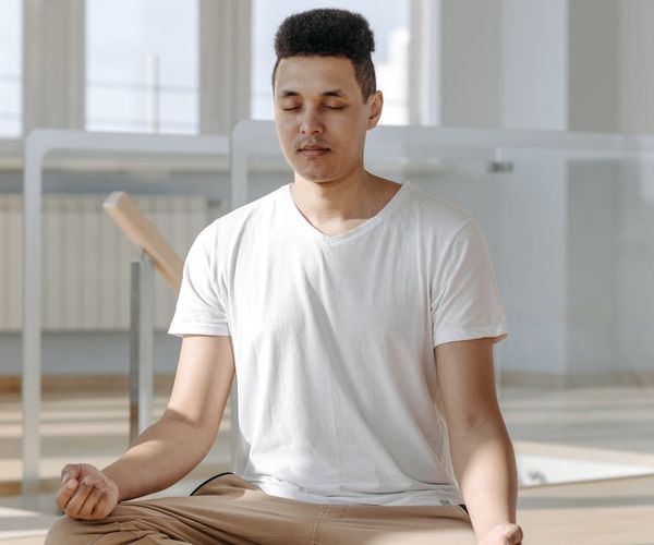A person meditating in a bright, sunlit room.