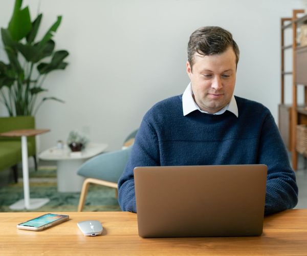 A person working at a clean desk with a laptop and a plant.